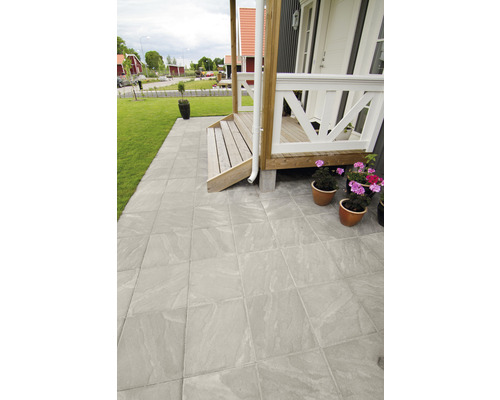 Uteplats med gatsten och veranda framför ett hus.