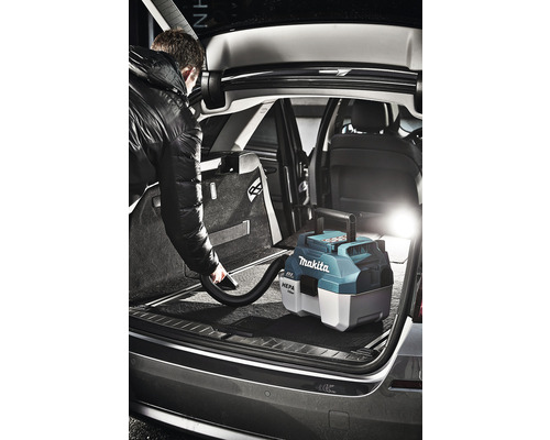 Man dammsuger bagageutrymmet på en bil med en sladdlös dammsugare från Makita.