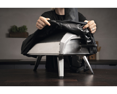 Person sätter ett skydd på en pizzaugn.