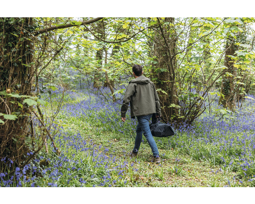 Man med väska går genom en skog med blommande hyacinter