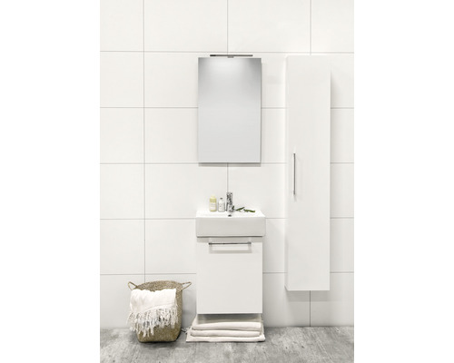 Ljust badrum med tvättställ, spegel, högskåp och tvättkorg.