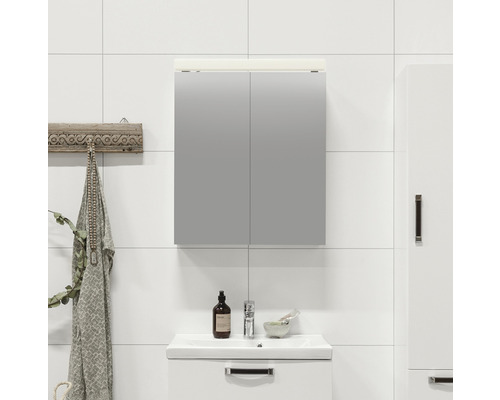 Badrum med spegelskåp, tvättställ och hängare mot en vitkaklad vägg