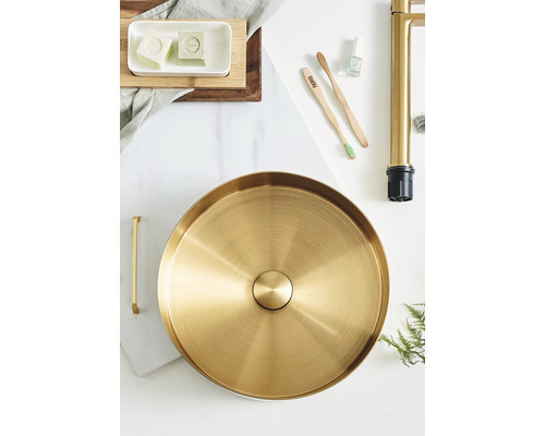 Foto av ett badrum med en handfatsskål, kran och diverse badrumstillbehör