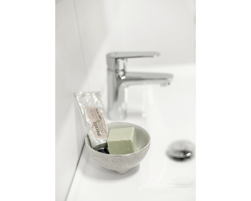 Handtvål, handkräm och skål på ett handfat med kran