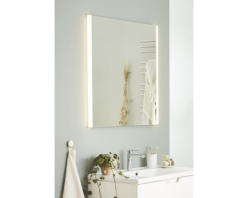 Badrum med belyst spegel, handfat och kran.