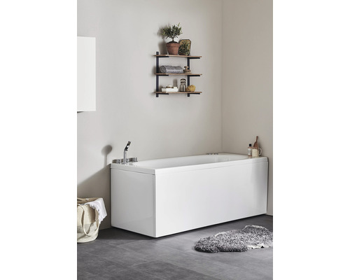 Modernt badrum med rektangulärt badkar, vägghylla och mörkt klinkergolv.