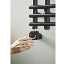 Hand manövrerar radiatortermostat på badrumsradiator
