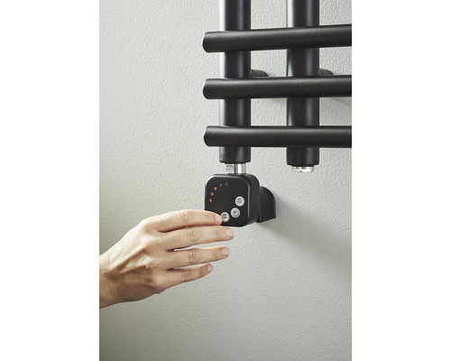 Hand manövrerar radiatortermostat på badrumsradiator