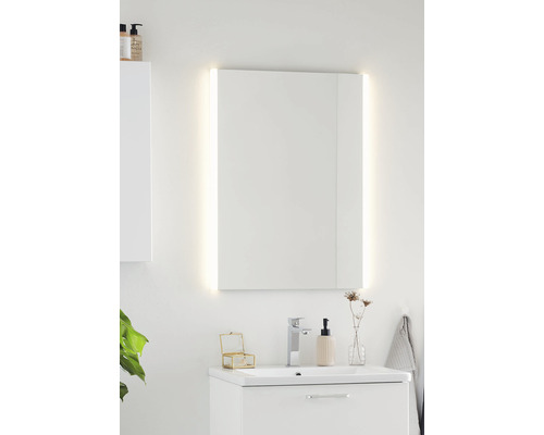 Badrum med belyst spegelskåp ovanför ett tvättställsskåp