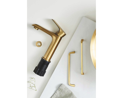 Gyllene tvättställsblandare med tillbehör på ljus bakgrund