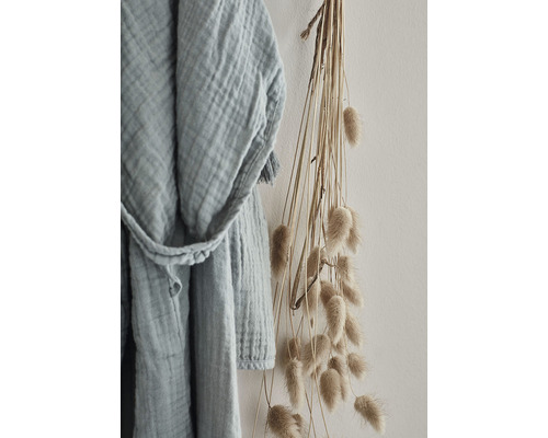 Lätt badrock i bomull bredvid en bukett torkade blommor