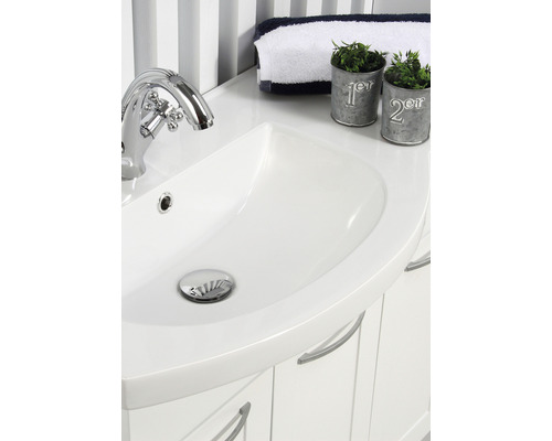 Detaljvy av ett vitt tvättställ med kromad armatur och dekorativa element