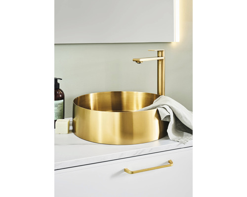 Gyllene tvättställsskål med blandare på ett tvättställsskåp