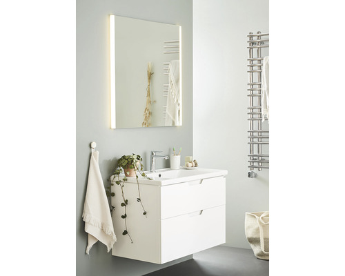 Badrum med tvättställsskåp, tvättställ, spegel med belysning och handdukstork i silver