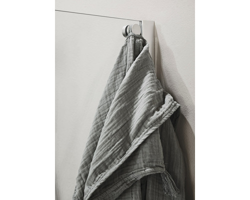 Grå musselinhandduk hänger på en handdukskrok