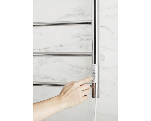 Närbild av en uppvärmd handdukstork med ett finger som justerar kontrollerna