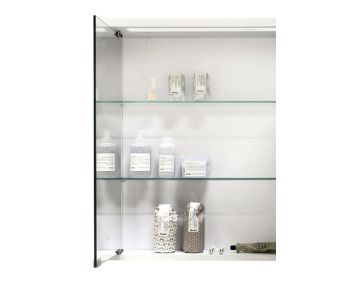 Vitt spegelskåp med glashyllor och diverse vårdprodukter