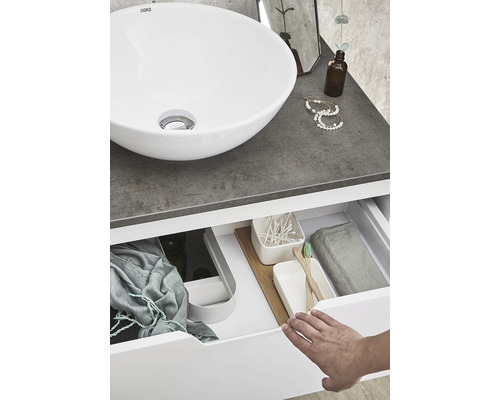 Badrum med runt handfat och öppen låda med diverse badrumsartiklar