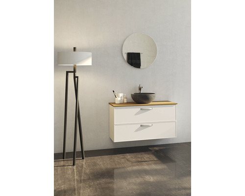 Badrumsmiljö med tvättställsskåp, handfat, spegel och golvlampa