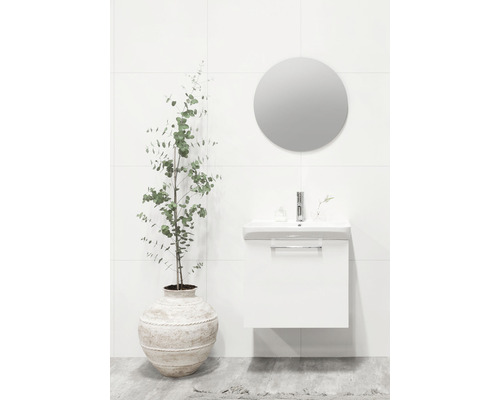 Badrum med vitt tvättställsskåp, rund spegel och krukväxt