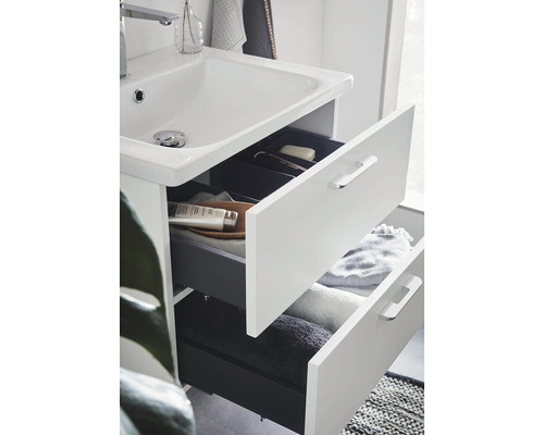 Badrumsskåp med handfat och öppna lådor för förvaring av handdukar och badrumsartiklar.