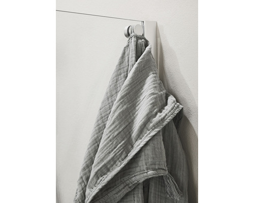 Textilhandduk med tofsar hänger på en handdukskrok
