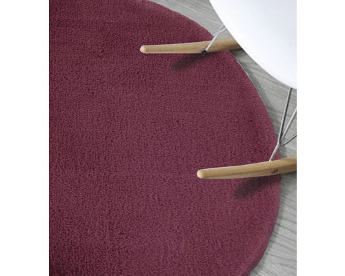 Detaljvy av en rund, texturerad matta under en stol