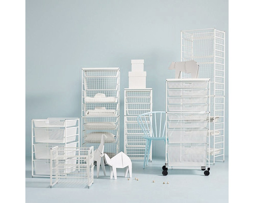 Diverse trådbackshyllor med textilier och dekorationer i ett rum.