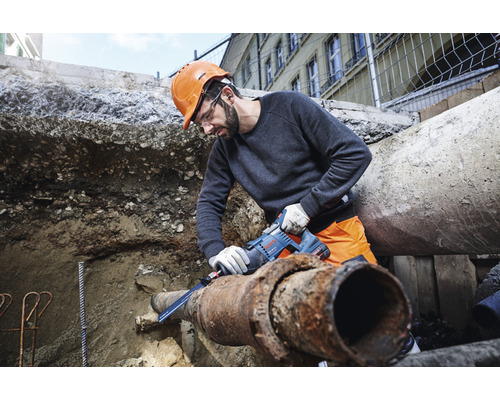 En man sågar ett rör med en sladdlös tigersåg från Bosch på en byggarbetsplats.