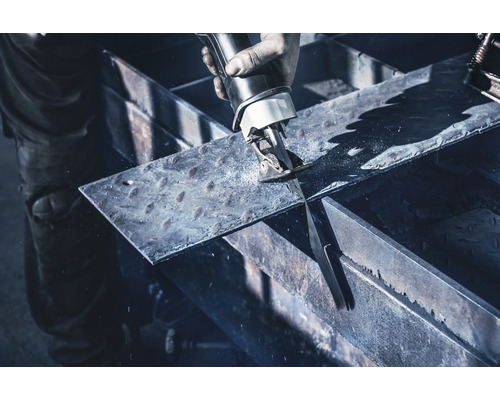 En person skär en metallplåt med en tigersåg.