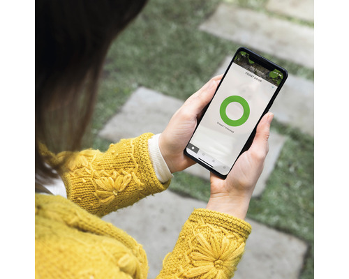 En person håller en smartphone med en smart hem-app som visar statusen för ytterdörren.