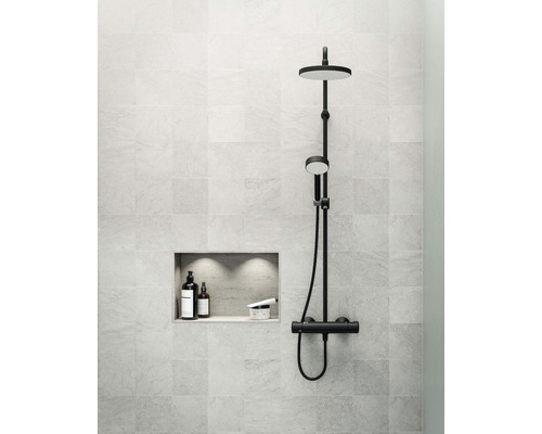 Modernt badrum med svart duschset, förvaringsfack och väggplattor.