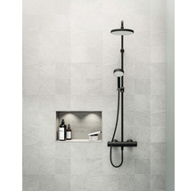 Modernt badrum med svart duschblandare och takdusch, inbyggd i en kakelvägg med nisch för förvaring av badrumsartiklar