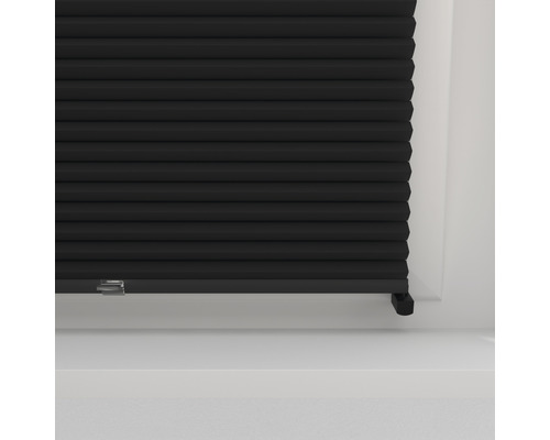 Närbild av en svart plisségardin på ett fönster