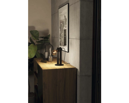 Dekorativ bordslampa på ett träskåp med krukväxt och inramad bild