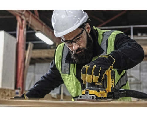 En arbetare använder en planslipmaskin från Dewalt för att slipa en bit trä