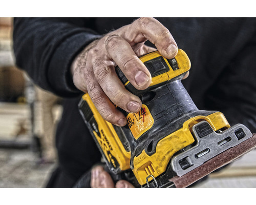 Närbild av en man som håller en DeWalt excenterslipmaskin.