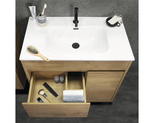 Tvättställsskåp i trä med öppen låda och diverse badrumsartiklar på handfatet