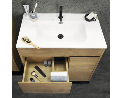 Tvättställsskåp i trä med öppen låda och diverse badrumsartiklar på ytan