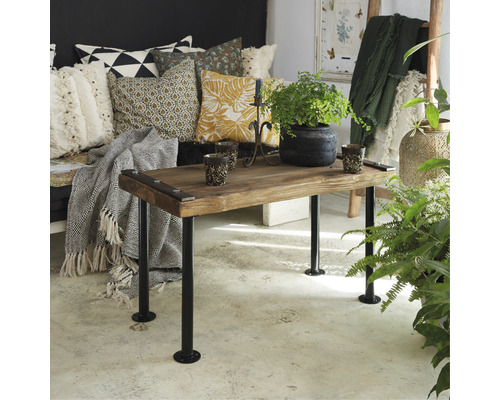 Vardagsrum med soffa, kuddar och ett träbord med växter och ljus