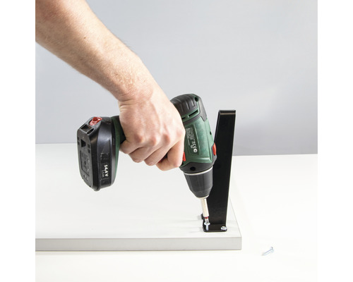 En person skruvar fast ett svart fäste på en vit yta med en sladdlös skruvdragare.