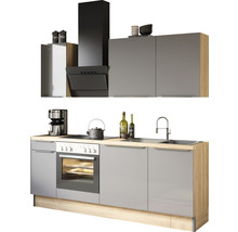 Modernt kök med grå skåp, diskho, spis och fläkt.