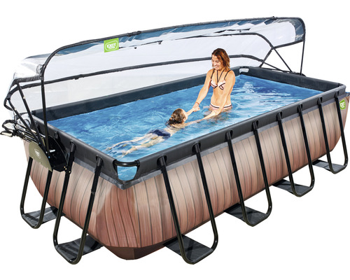 Rektangulär pool med skydd, stege och trälook, där en kvinna hjälper ett barn att simma.