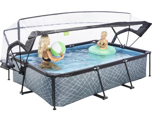 Rektangulär pool med tak, fylld med vatten, där en kvinna med en boll och ett barn med en badring leker