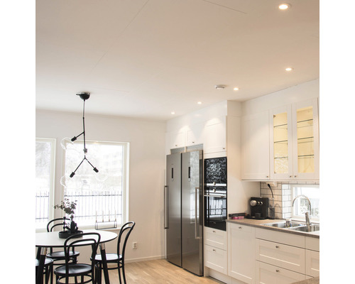 Ljust kök med matbord, stolar, pendellampa och integrerat kök