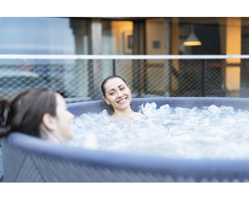 Två kvinnor kopplar av i en uppblåsbar bubbelpool utomhus