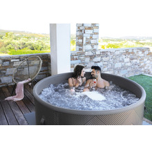 Uppblåsbar bubbelpool med två personer på en terrass med stenelement och en stol