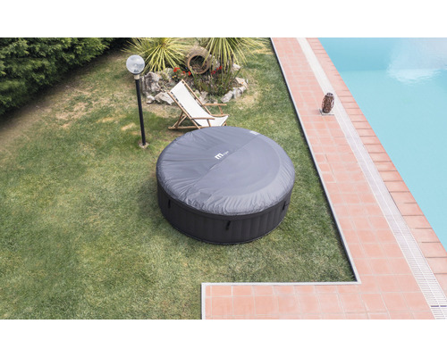 Uppblåsbar rund bubbelpool med lock i trädgården bredvid poolen.