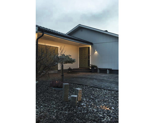 Husfasad med belysning, stenar och växter