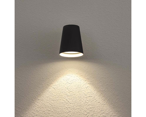 Svart vägglampa belyser väggen